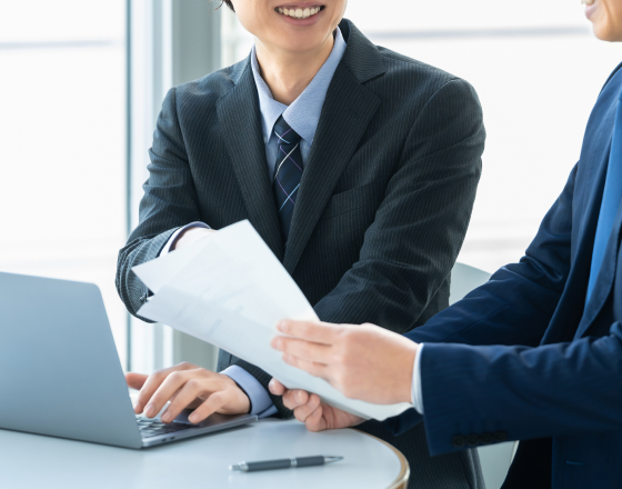 資料を手に取り会議するサラリーマンの男性2人