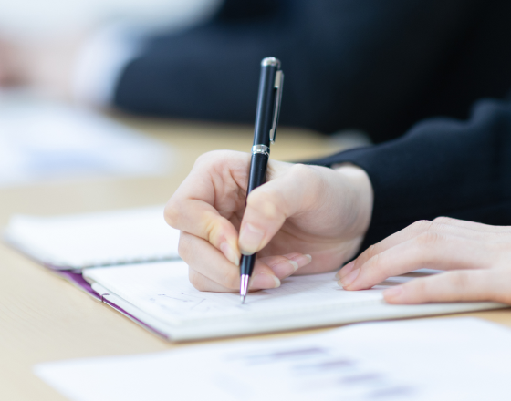 ノートにボールペンで書き込む女性の手